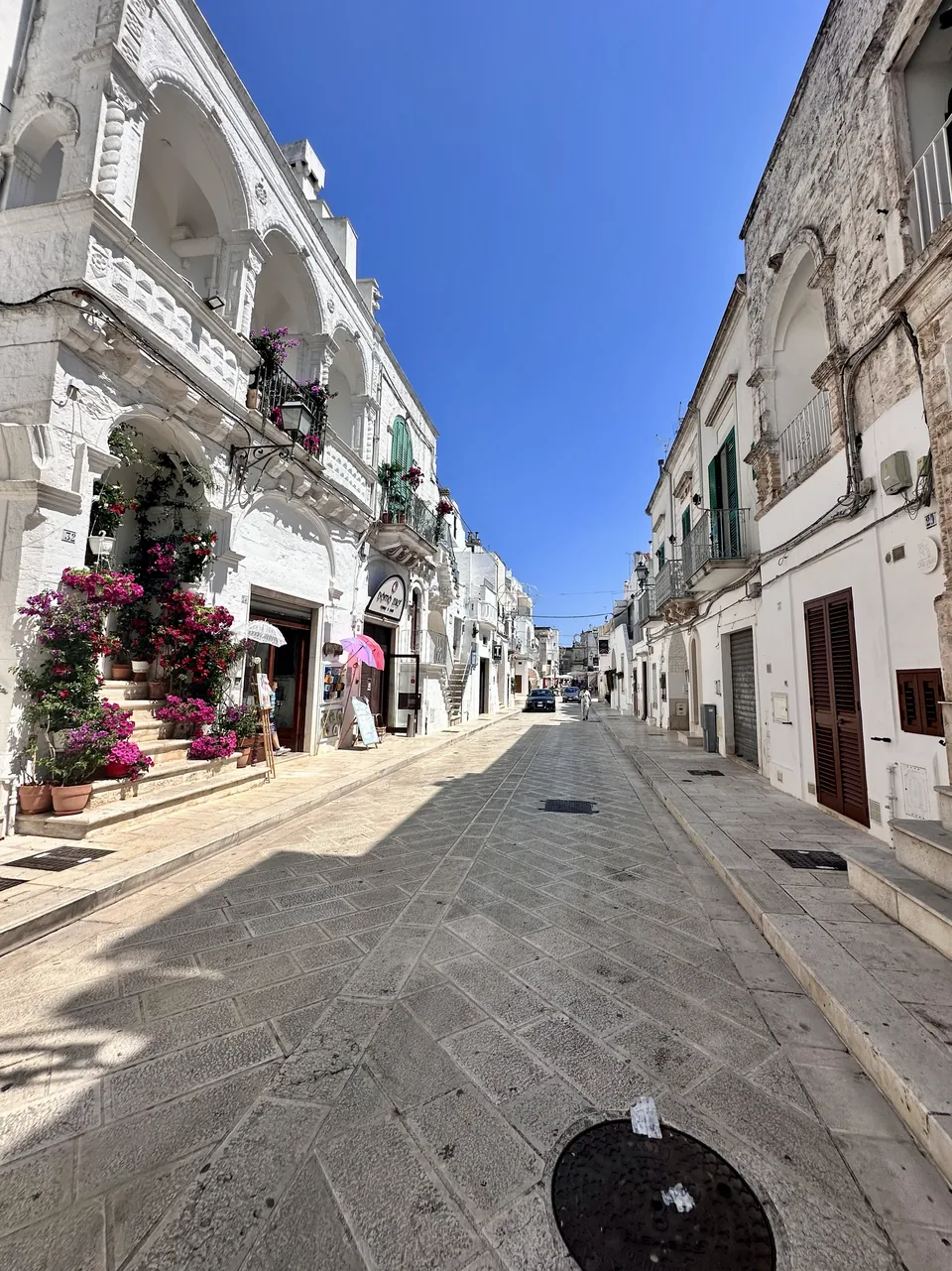 Rua de Cisternino com construções tradicionais e estabelecimentos comerciais