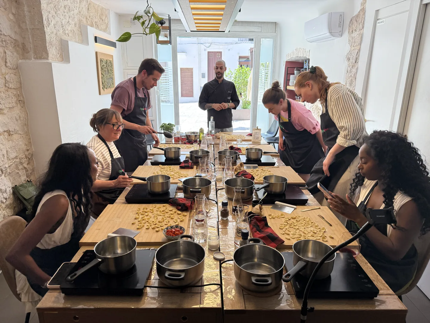 Participantes de uma cooking class do Mani e Farina com chef italiano e estação de preparo de massas