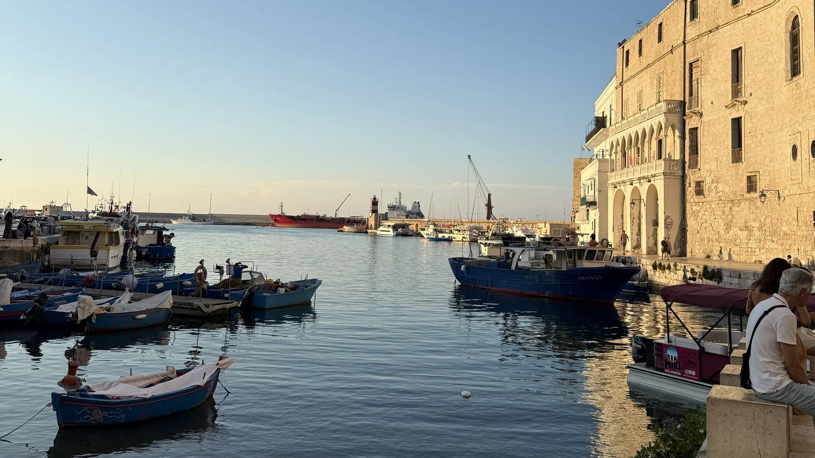 Porto Antico de Monopoli com barcos de pesca e construções históricas ao entardecer