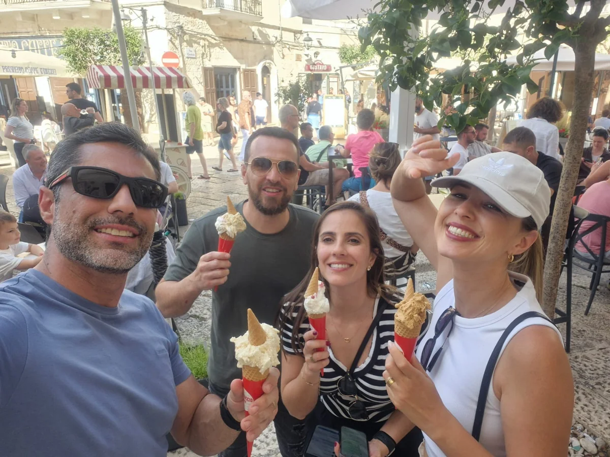 Grupo de amigos tomando sorvete em uma praça movimentada de Monopoli